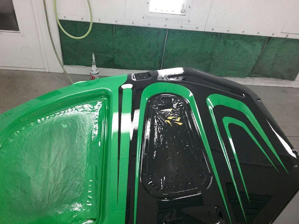 Green car with black roof and hood accents in a garage, viewed from above