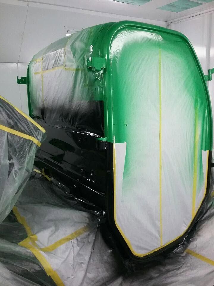 Masked industrial machine in a workshop, wrapped in green and white protective plastic.