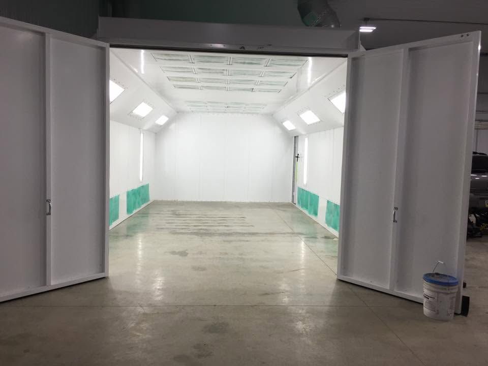 Empty white room with open double doors, teal wall panels, and a concrete floor