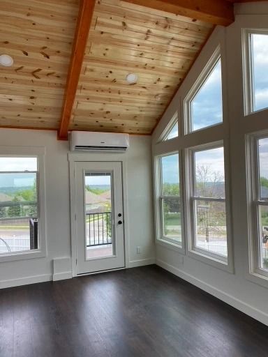 Interior room with wood ceiling, large windows, and dark floor; air conditioning unit above door.