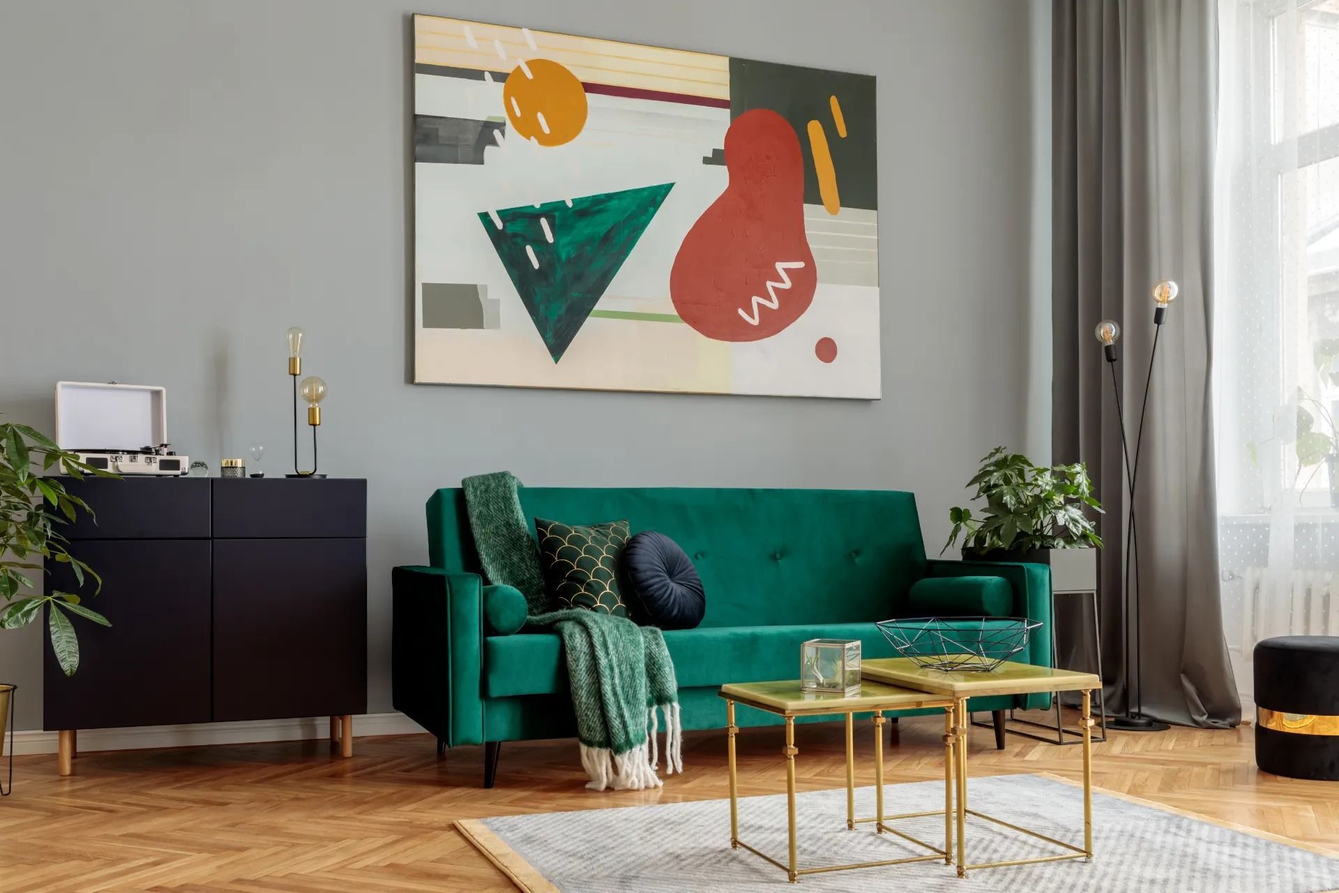 Living room with emerald green sofa, abstract art, and gold accents.