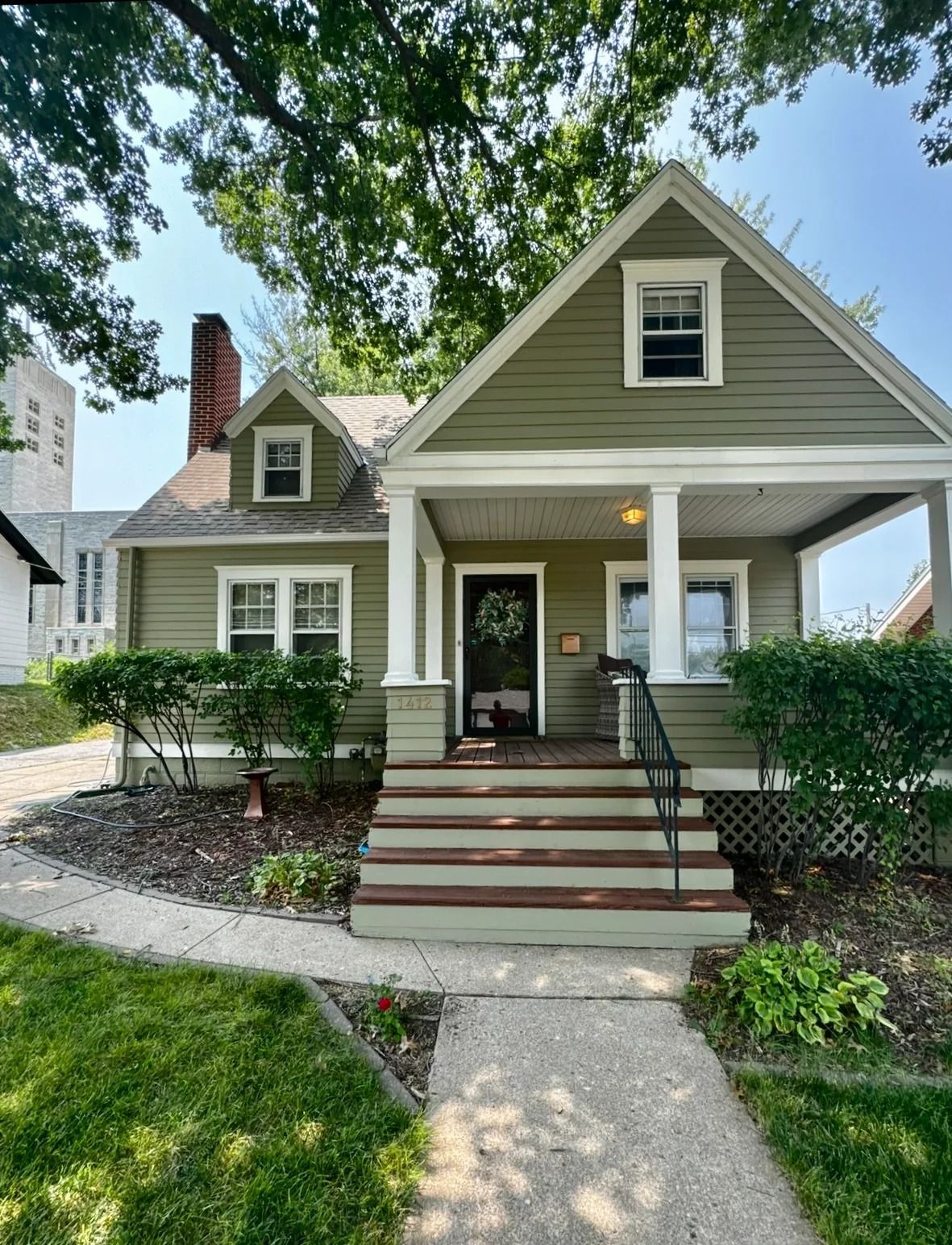 Green Craftsman-style house with porch, steps, and a walkway.