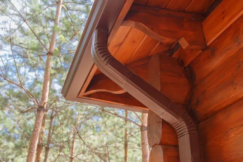 Brown guttering on a wooden building, with trees in the background.