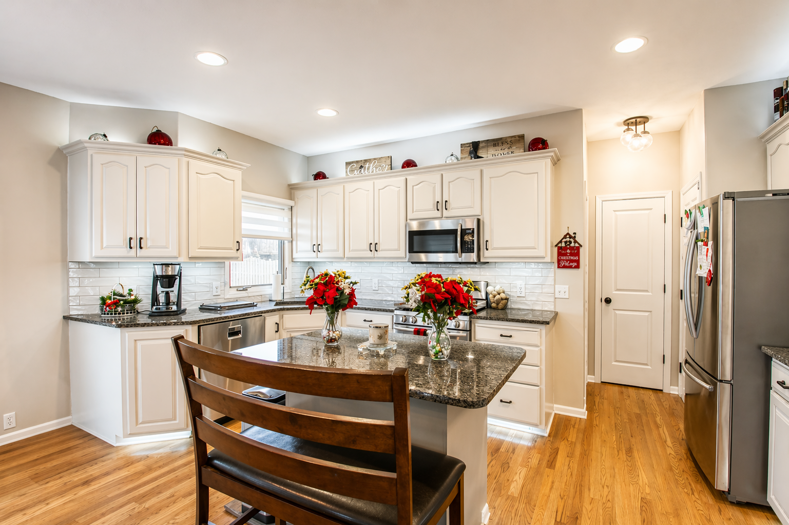 Bright modern kitchen with white cabinets, granite island, and wooden dining chairs