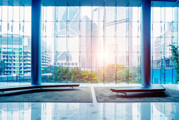 Bright modern office lobby with floor-to-ceiling glass, city view, and sunlight on polished floor