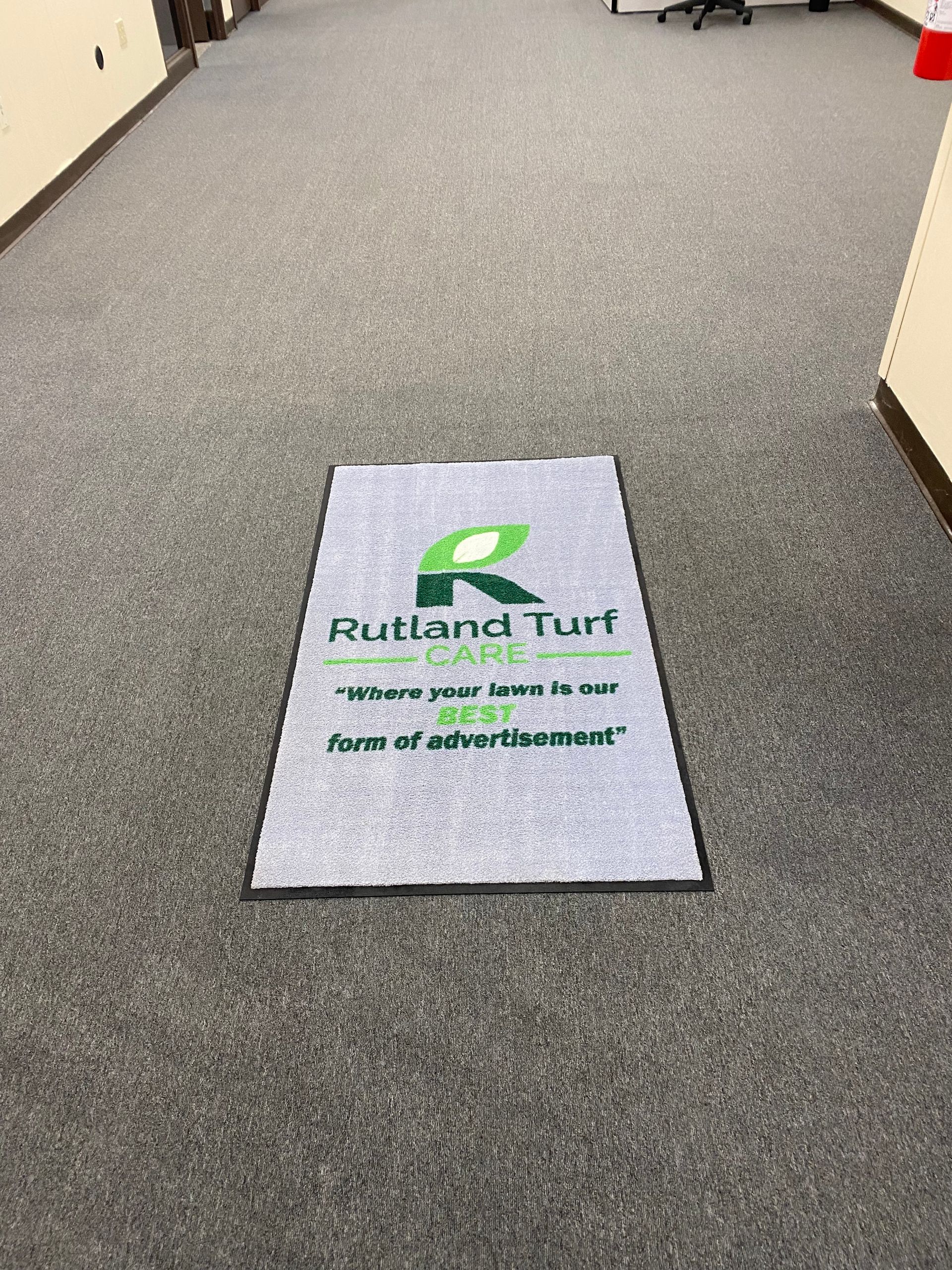A rug with the word rutland turf on it is on the floor in a hallway.