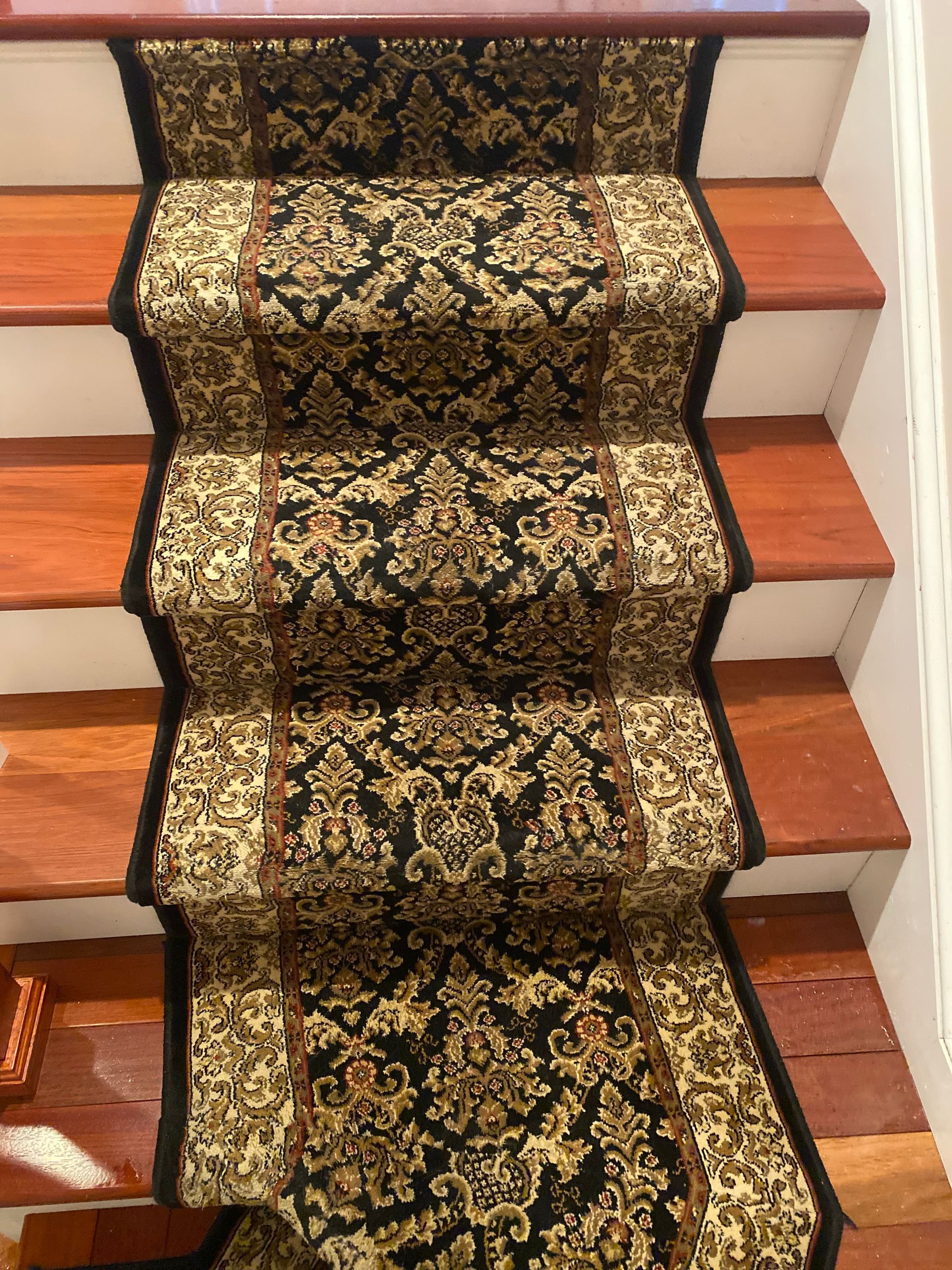 A staircase with a black and gold carpet on it.