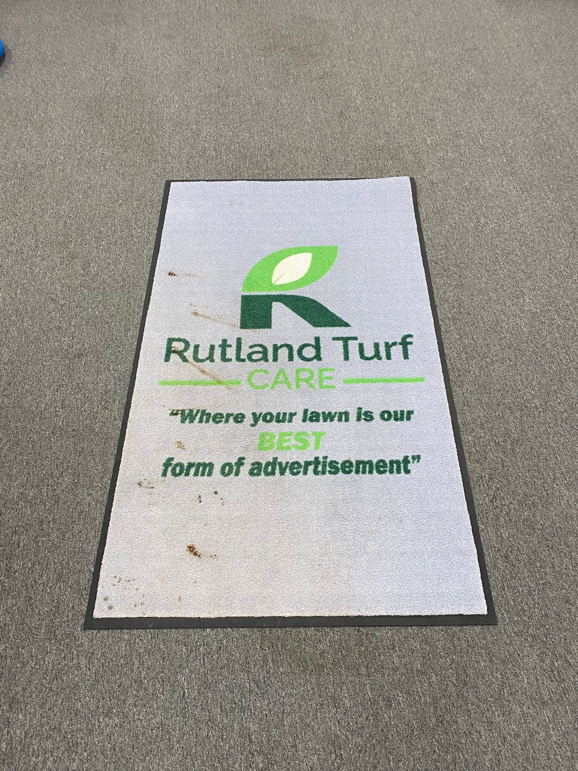 A rug with the words `` rutland turf care '' written on it is on the ground.
