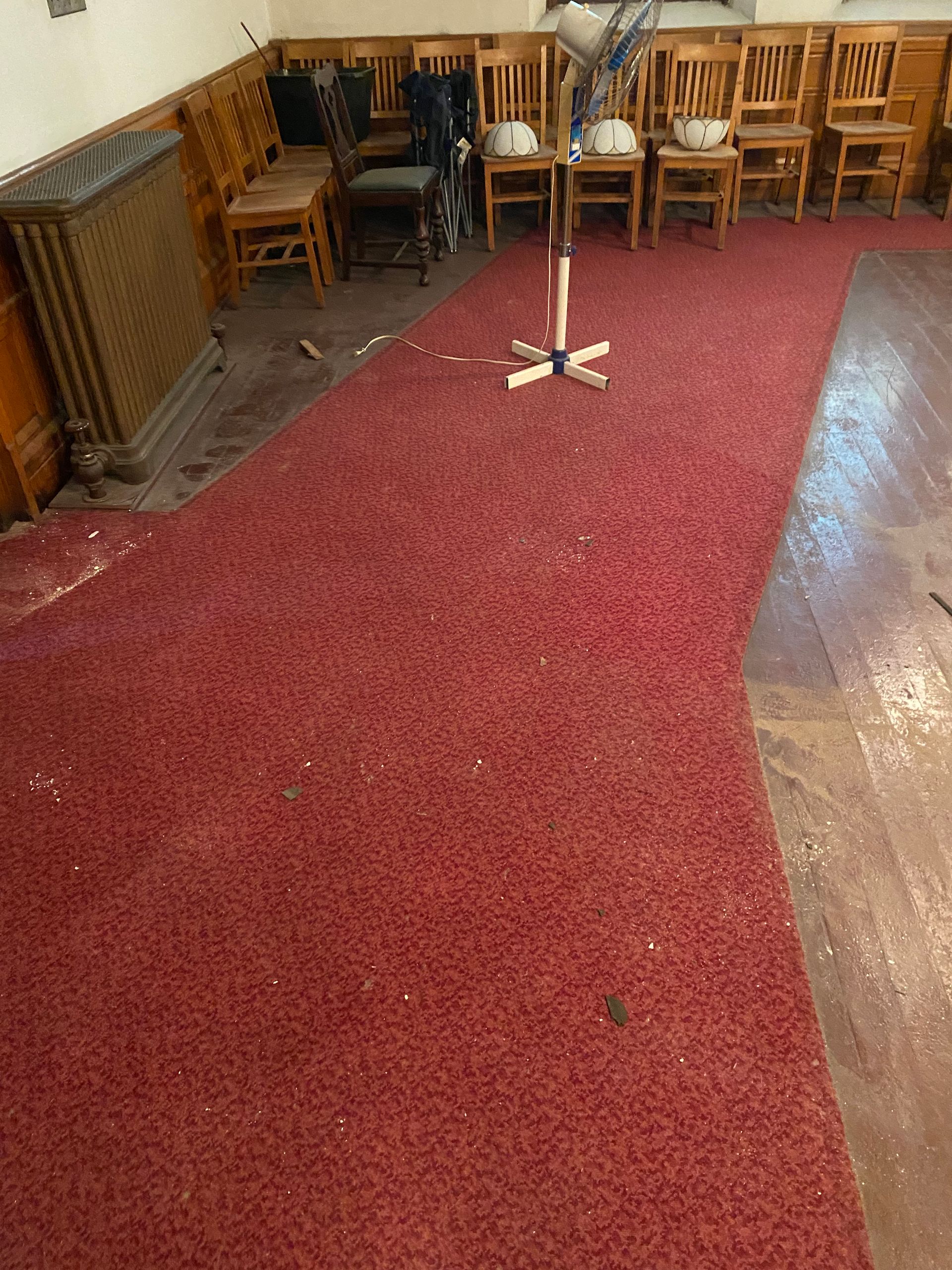 A red carpeted floor in a room with chairs and a microphone.
