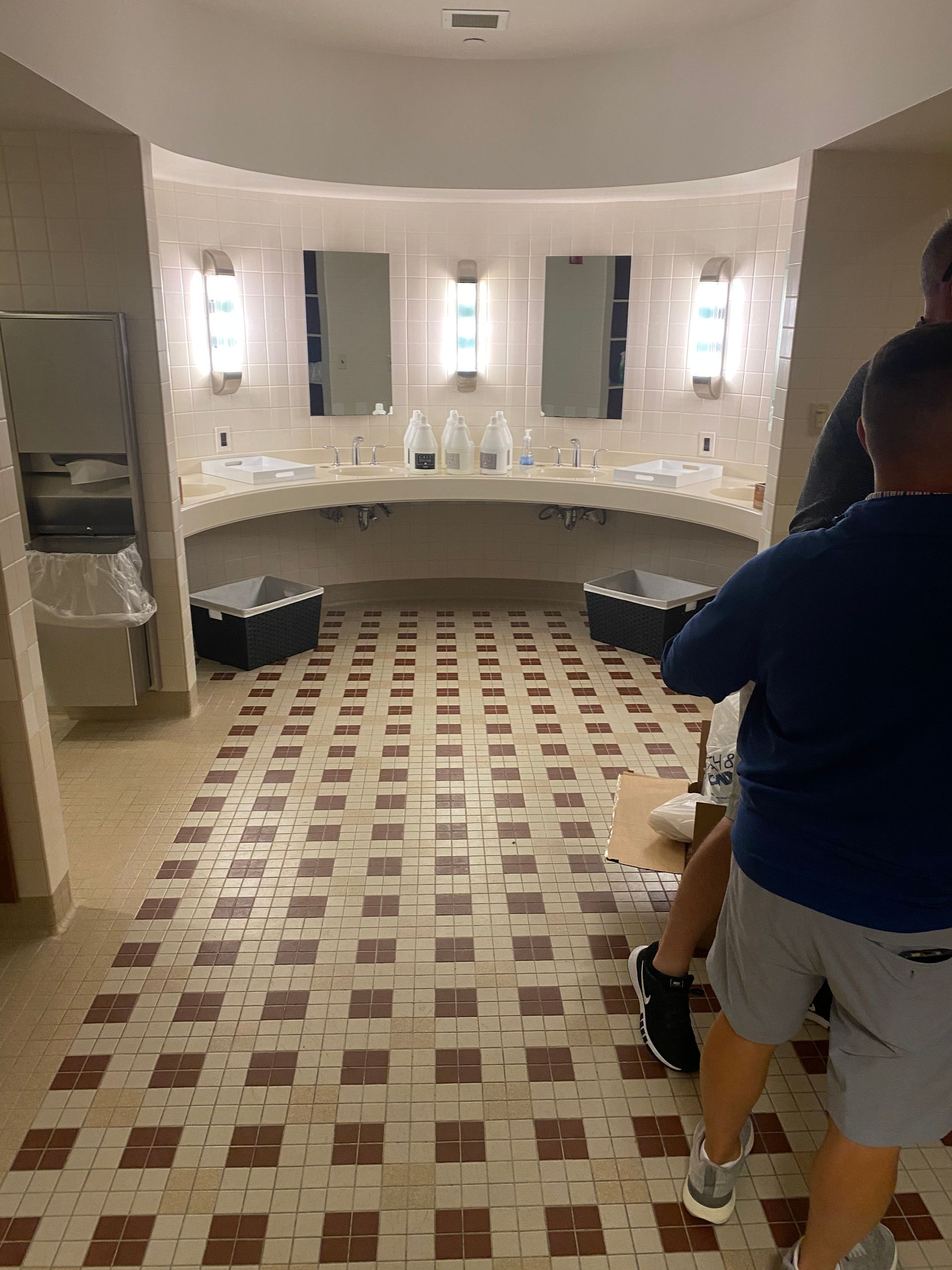 Two men are standing in a bathroom with a tiled floor.