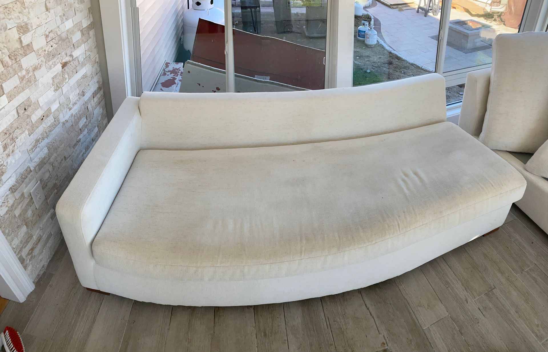 A white couch is sitting in a living room next to a window.