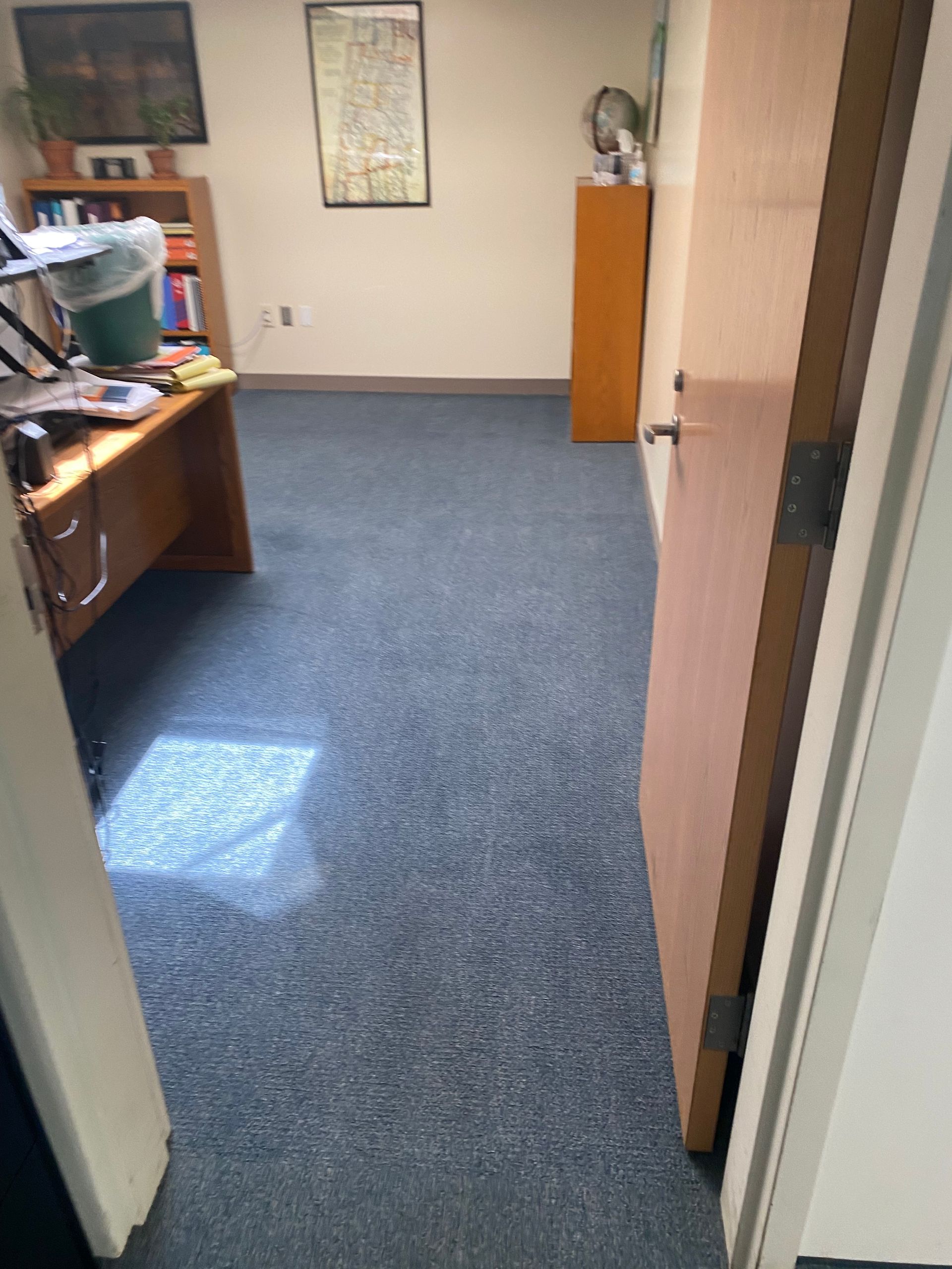 A room with a desk and a trash can in it