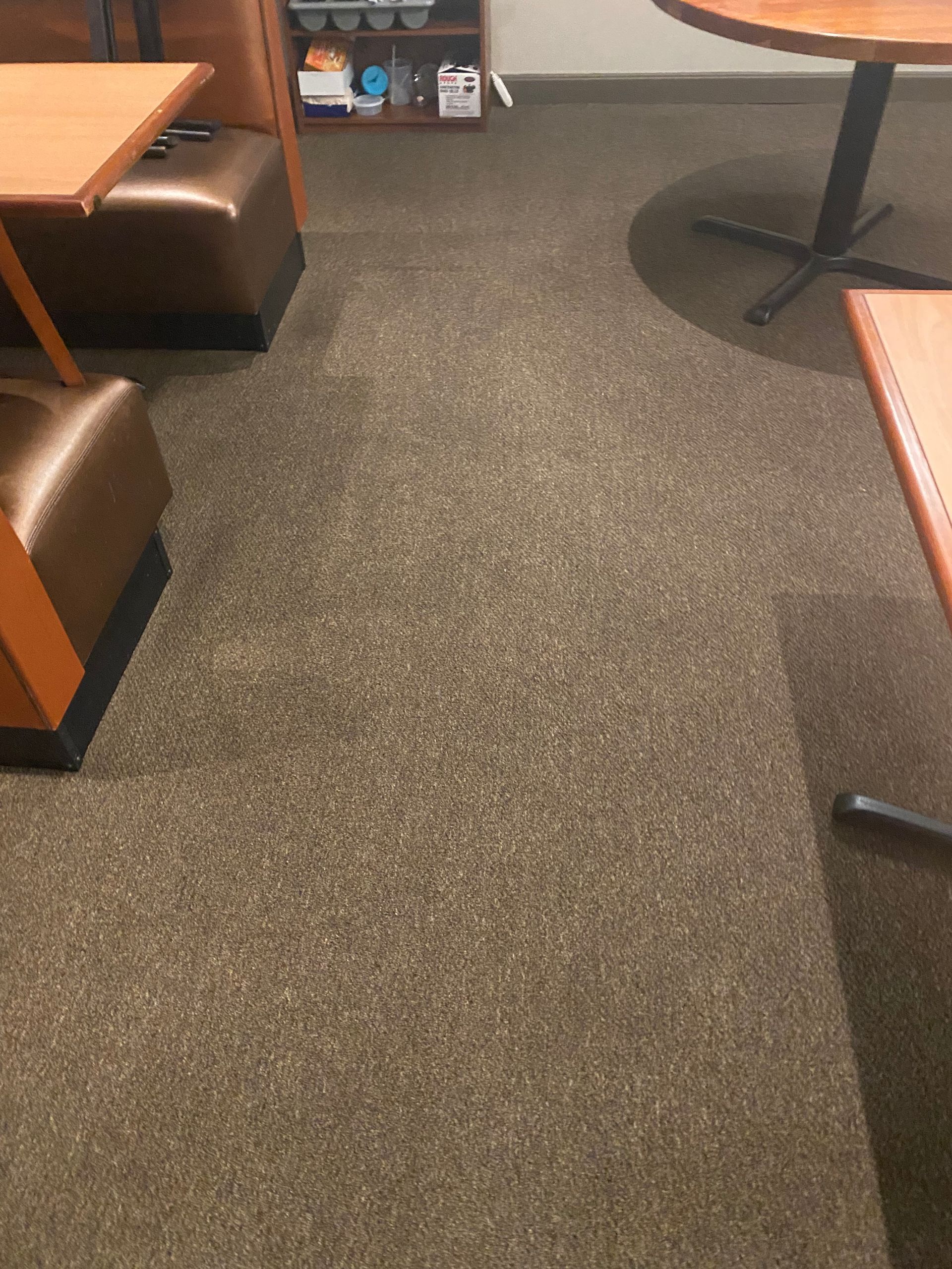 A restaurant with tables and chairs and a carpeted floor.