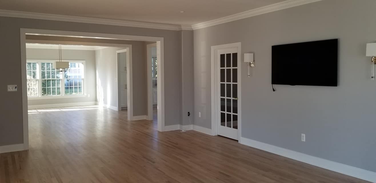 An empty living room with a flat screen tv on the wall.