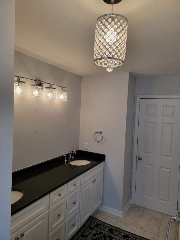 A bathroom with two sinks and a light fixture hanging from the ceiling.