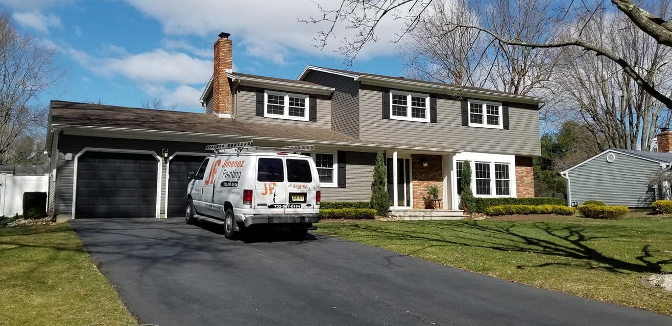 A white van is parked in front of a large house.