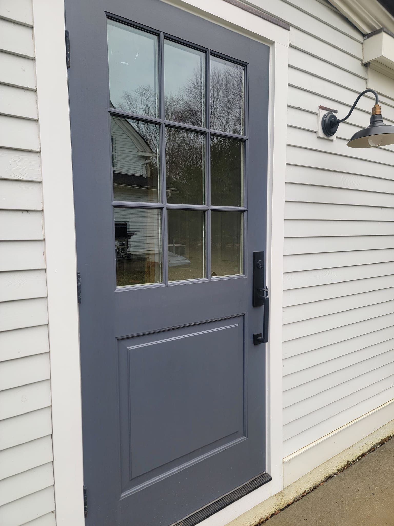 A gray door is on the side of a white house