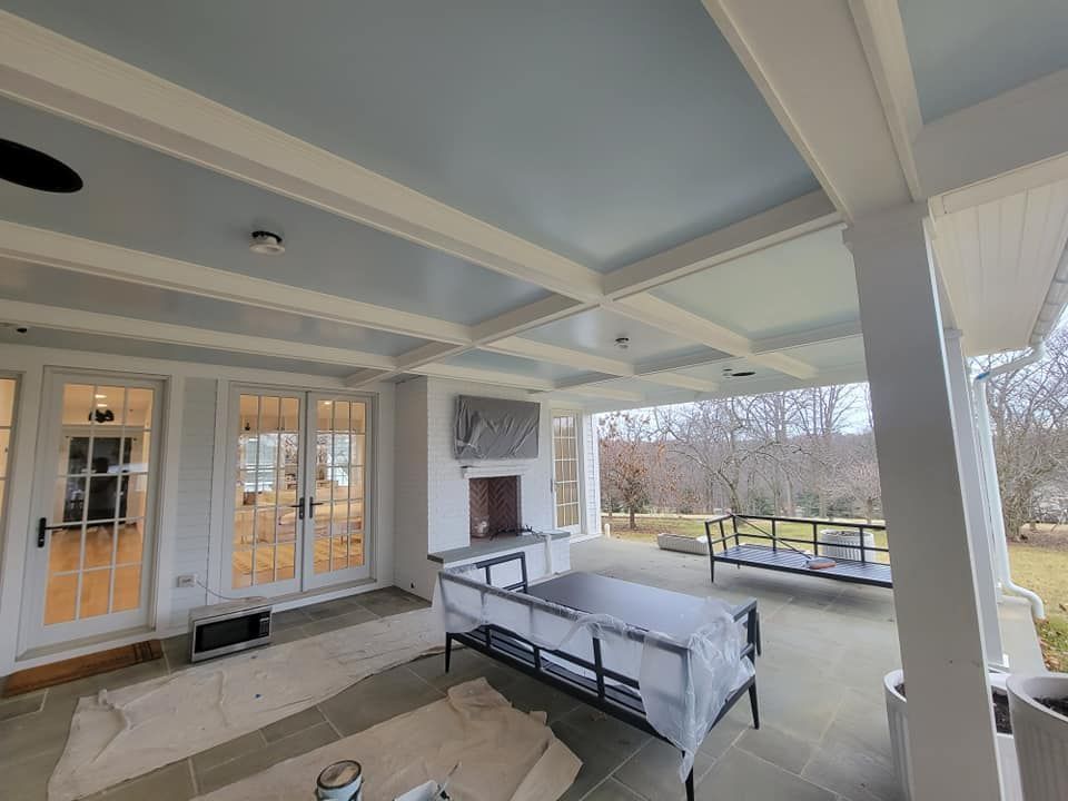 A large porch with a ceiling fan and a fireplace.