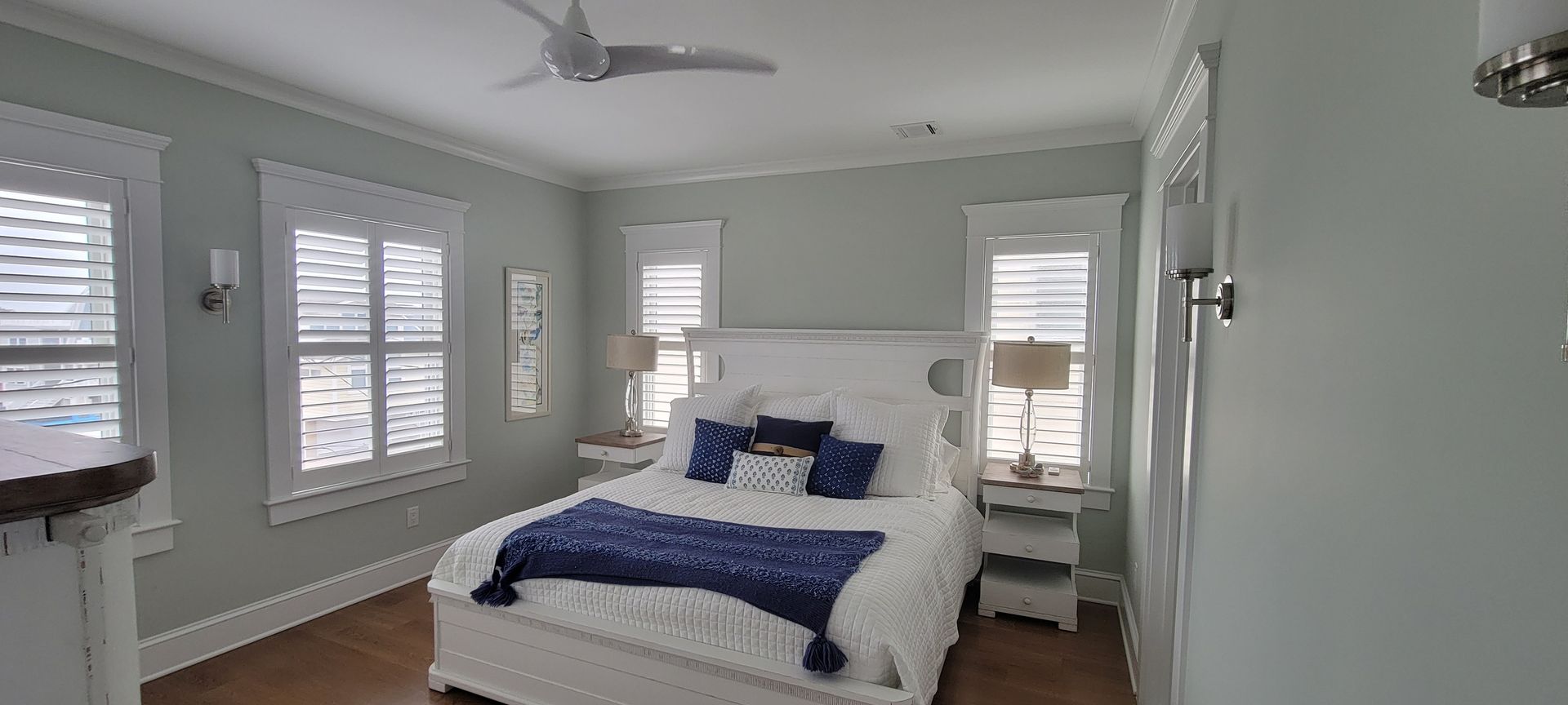 There is a bed in the middle of the room with a ceiling fan.