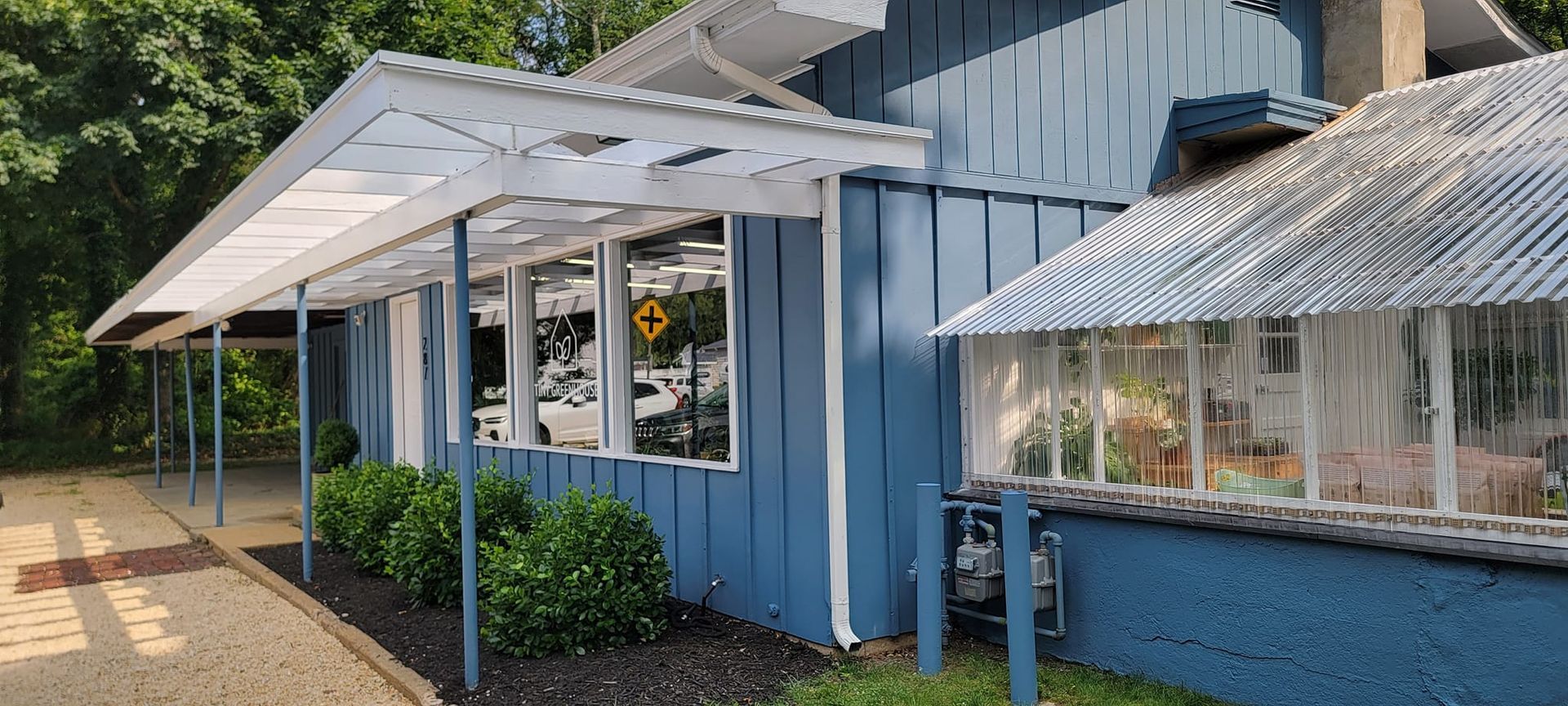 A blue building with a white roof and a covered walkway.