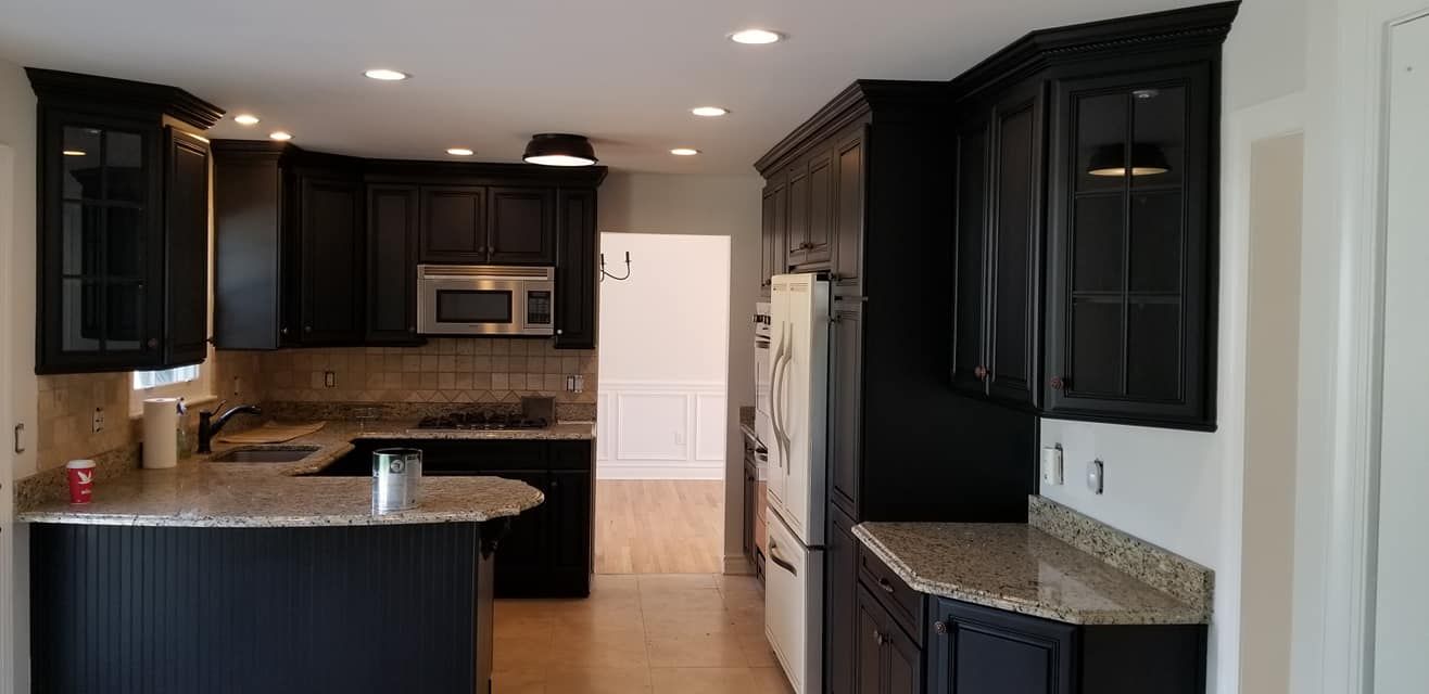 A kitchen with black cabinets and granite counter tops.