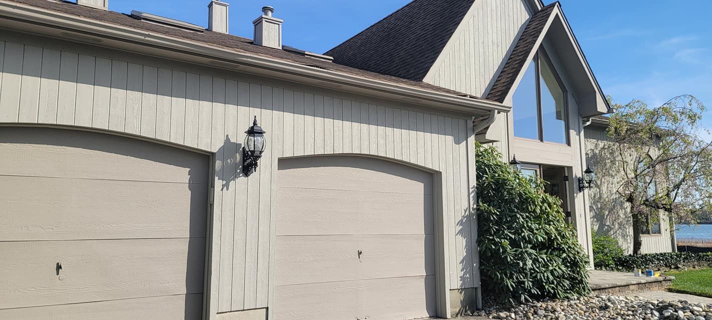 A large house with two garage doors and a large window.