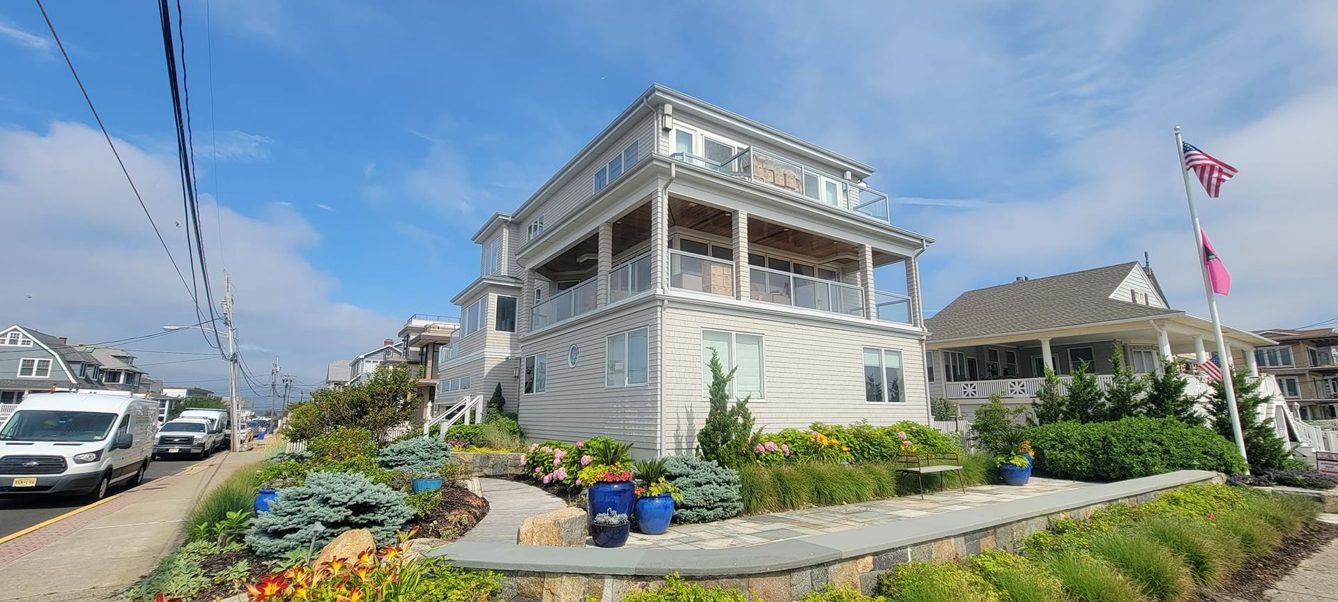 A large white house is sitting on top of a hill next to a street.