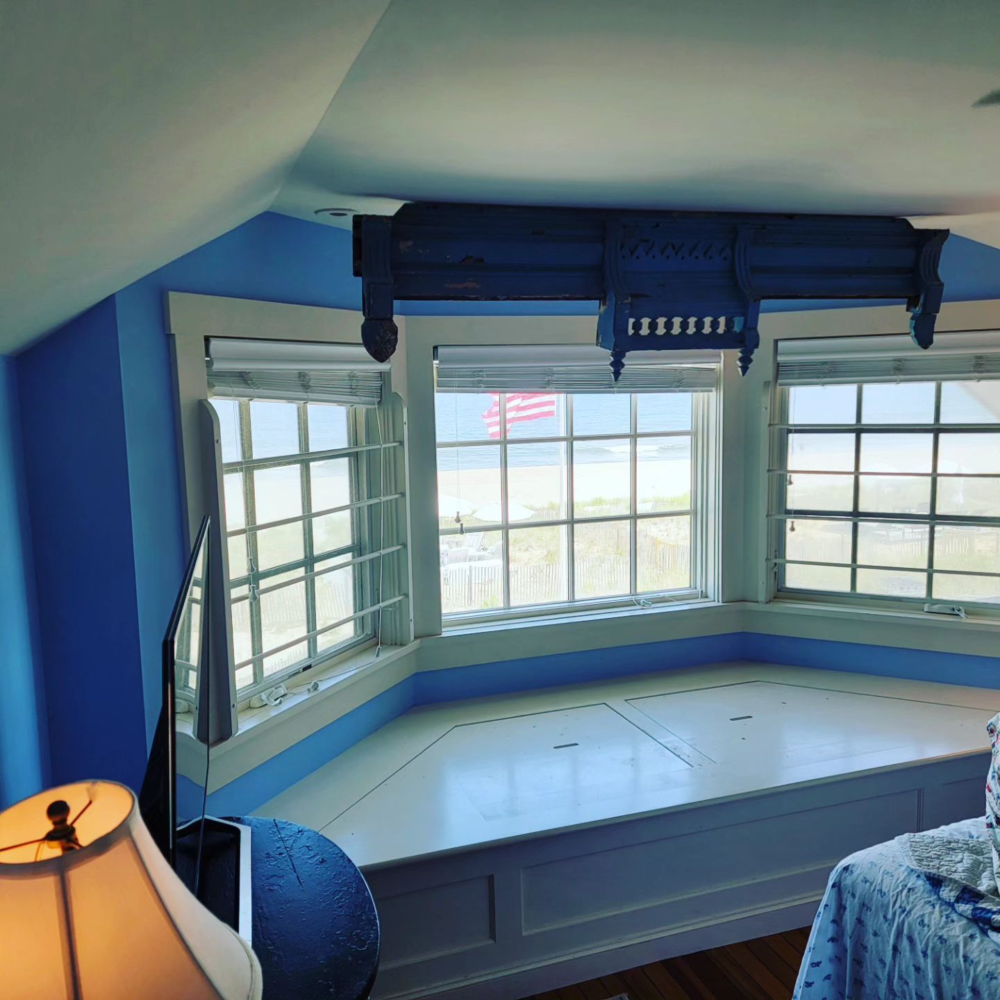 A bedroom with a large bay window and a lamp