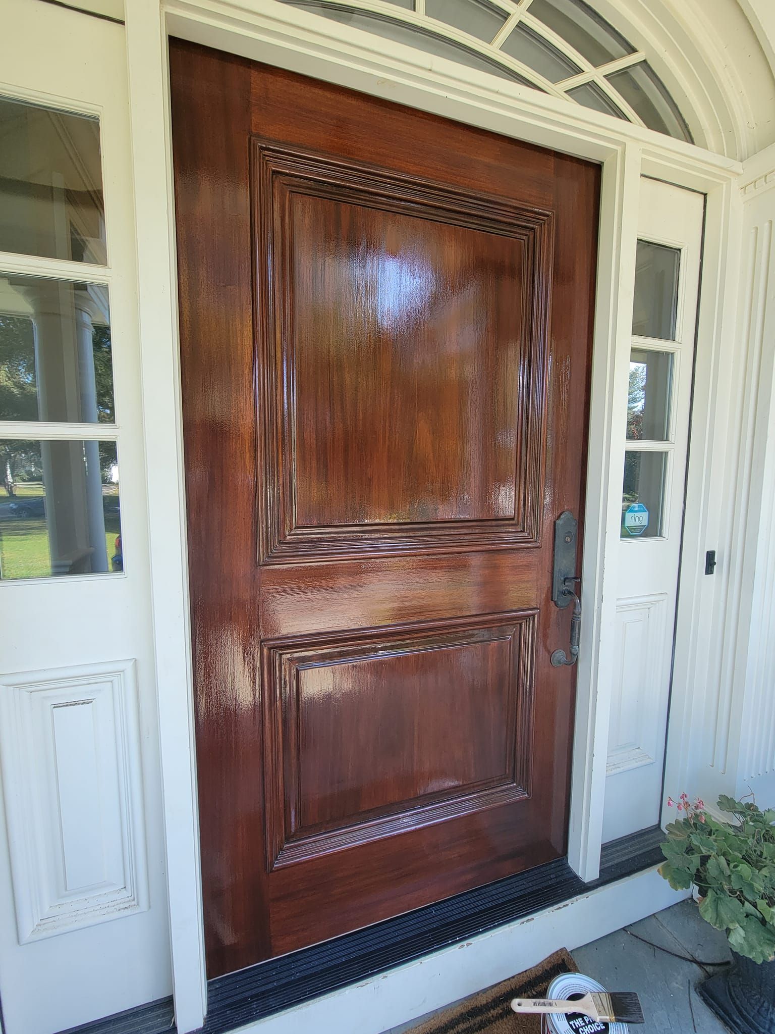 A large wooden door with a white frame is sitting on a porch.