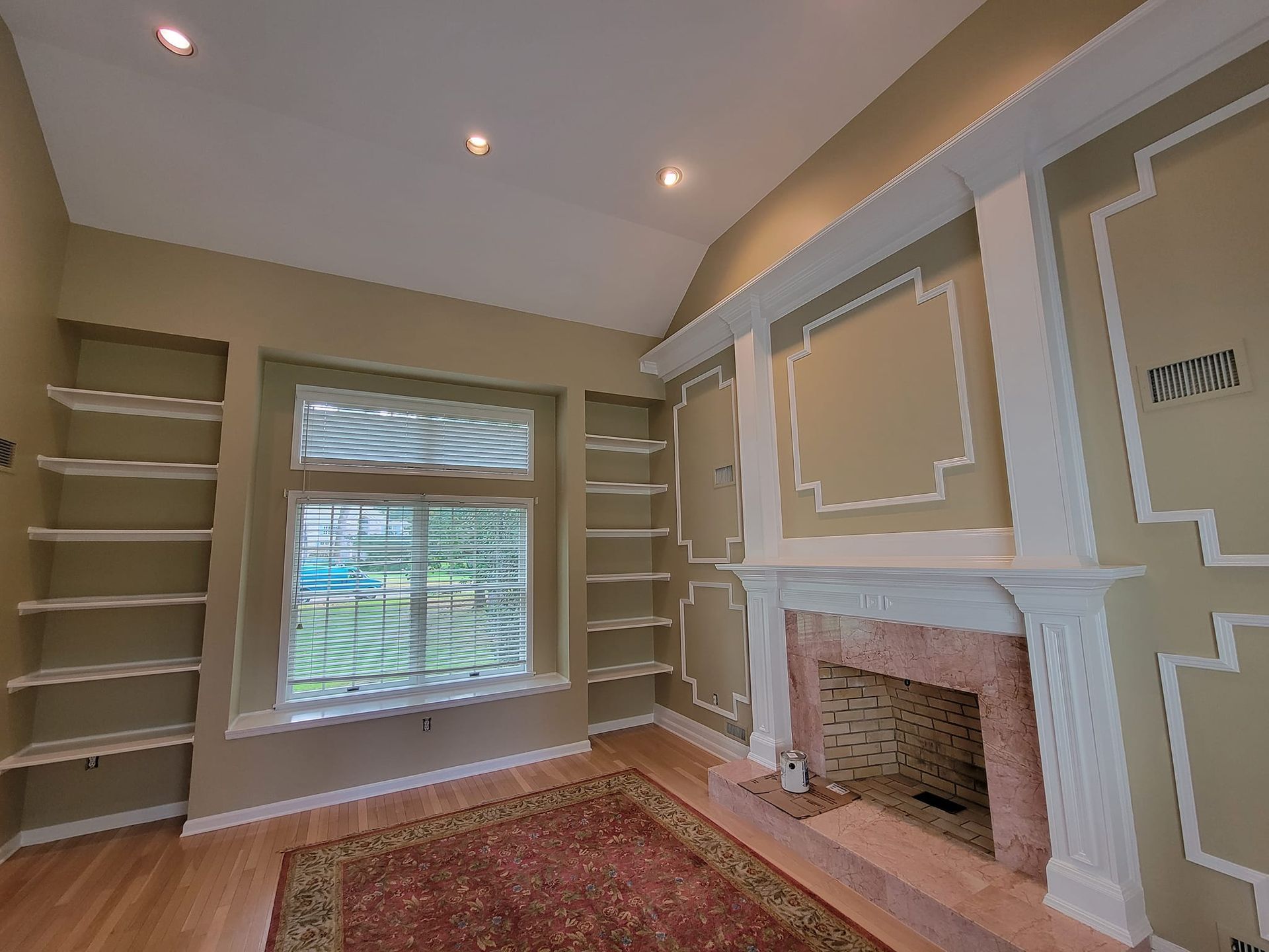 An empty living room with a fireplace and shelves