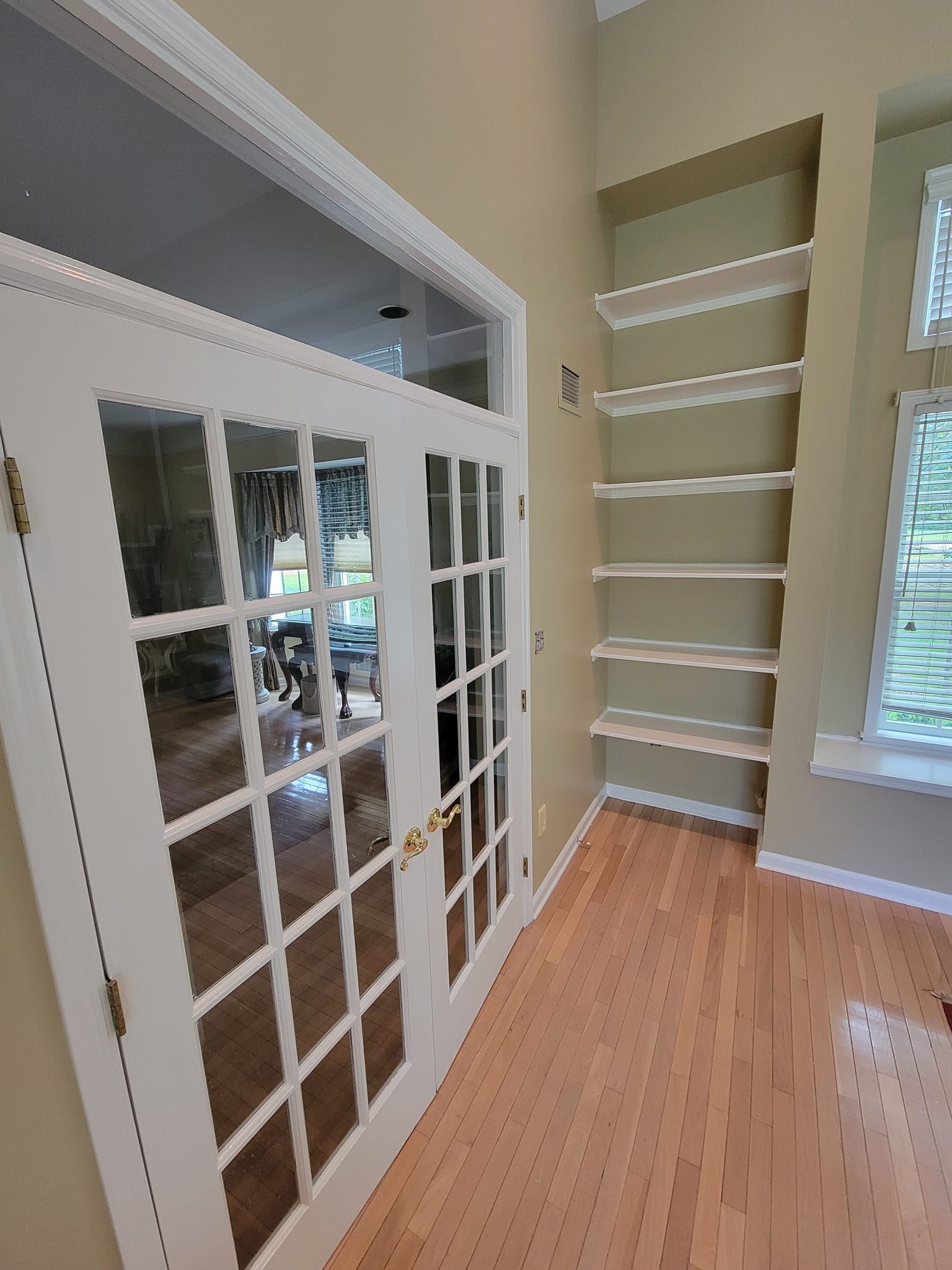 A hallway with french doors and shelves in a house