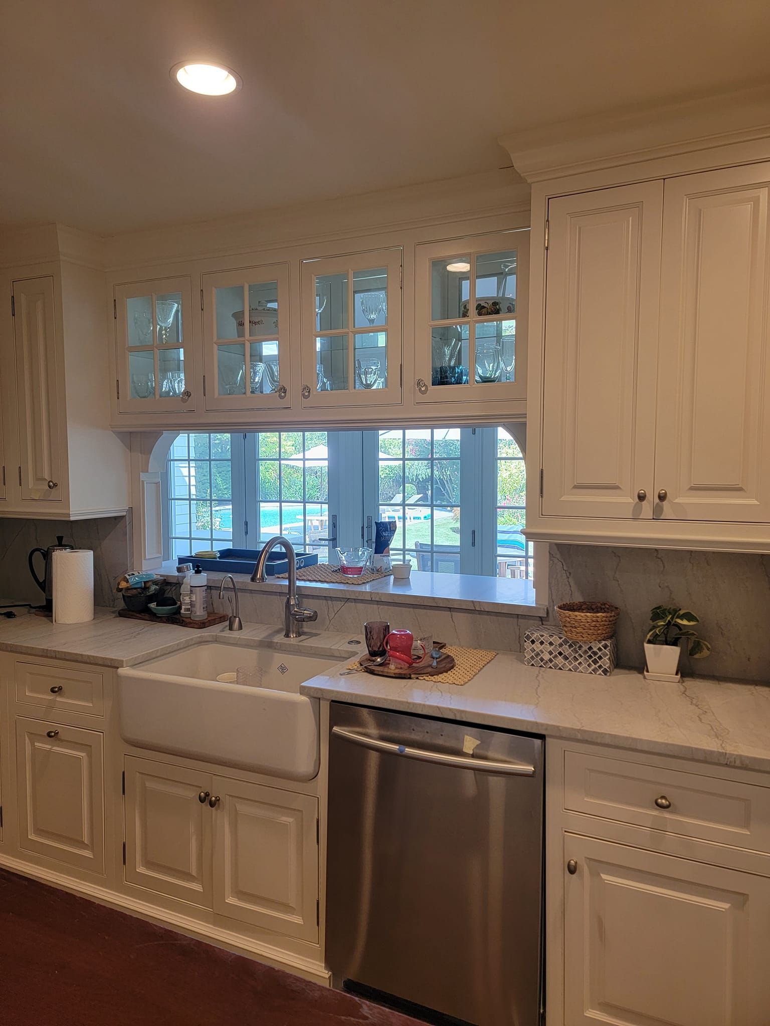 A kitchen with white cabinets , stainless steel appliances , a sink and a window.