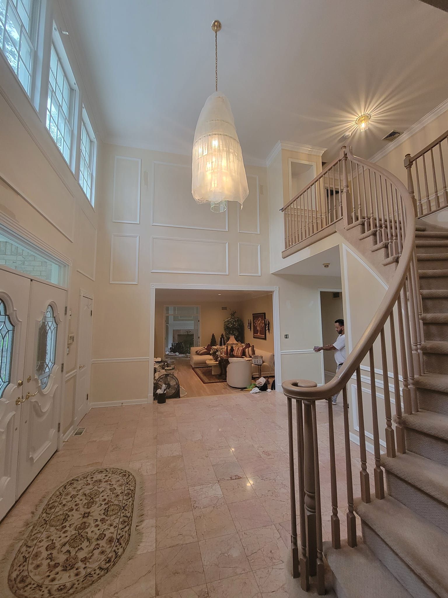 A large hallway with stairs and a chandelier hanging from the ceiling
