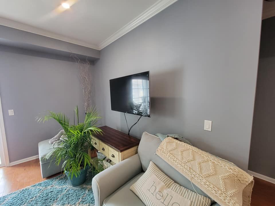 A living room with a couch and a flat screen tv on the wall.