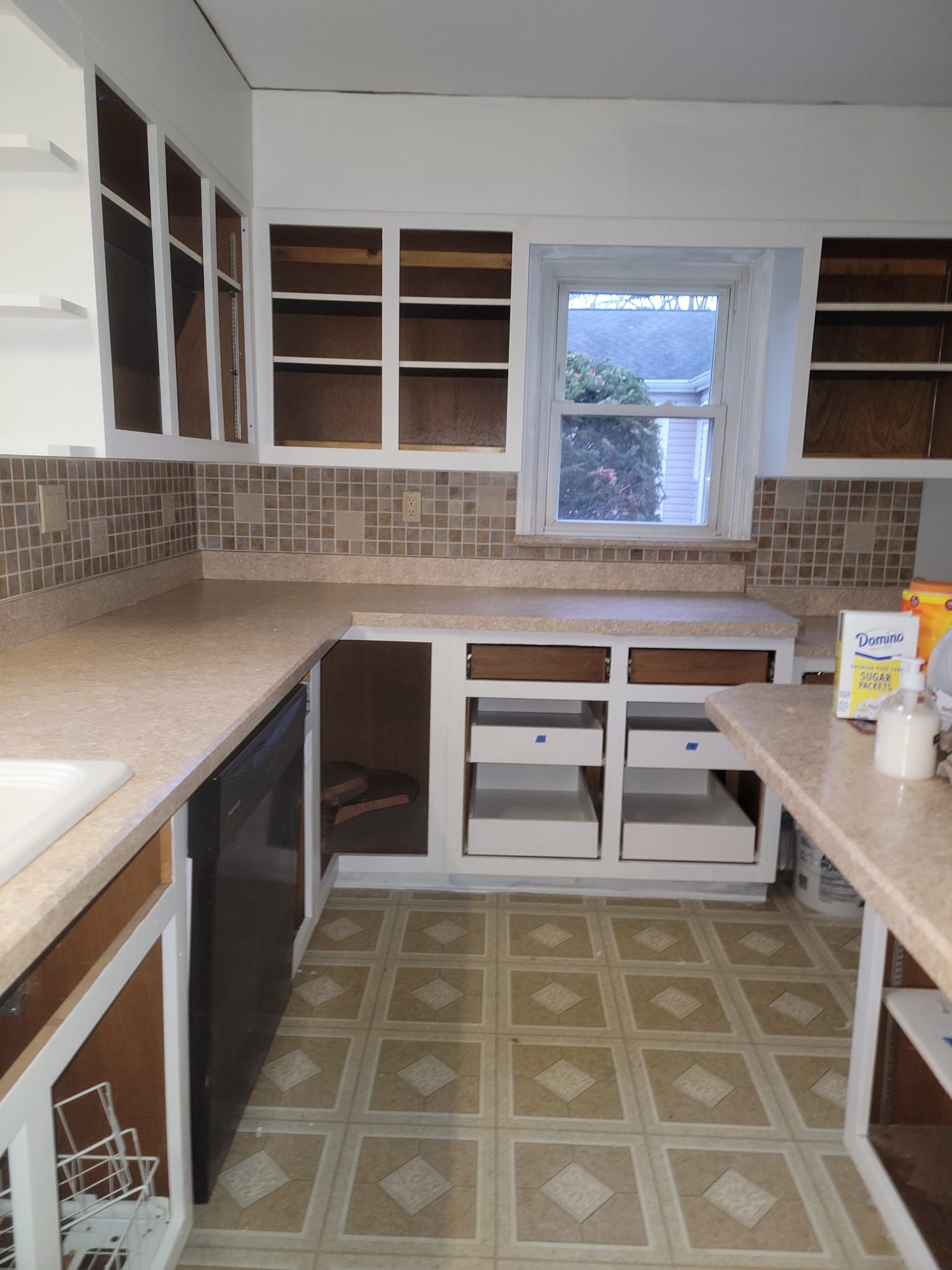 A kitchen with empty cabinets and a dishwasher
