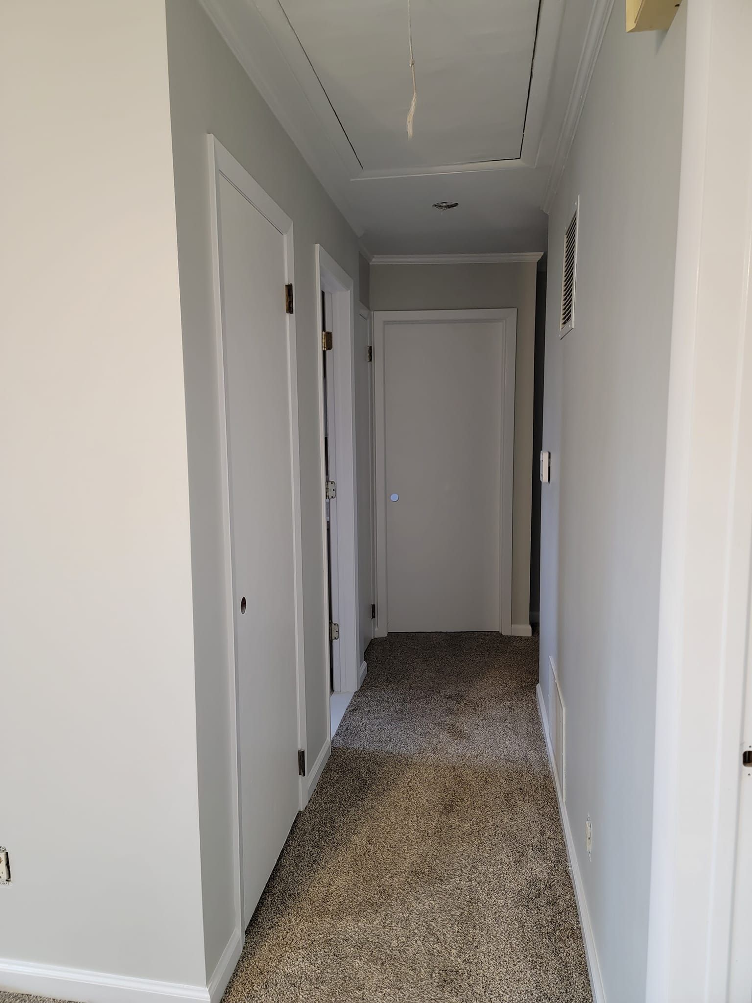 A long hallway with a carpeted floor and white walls.