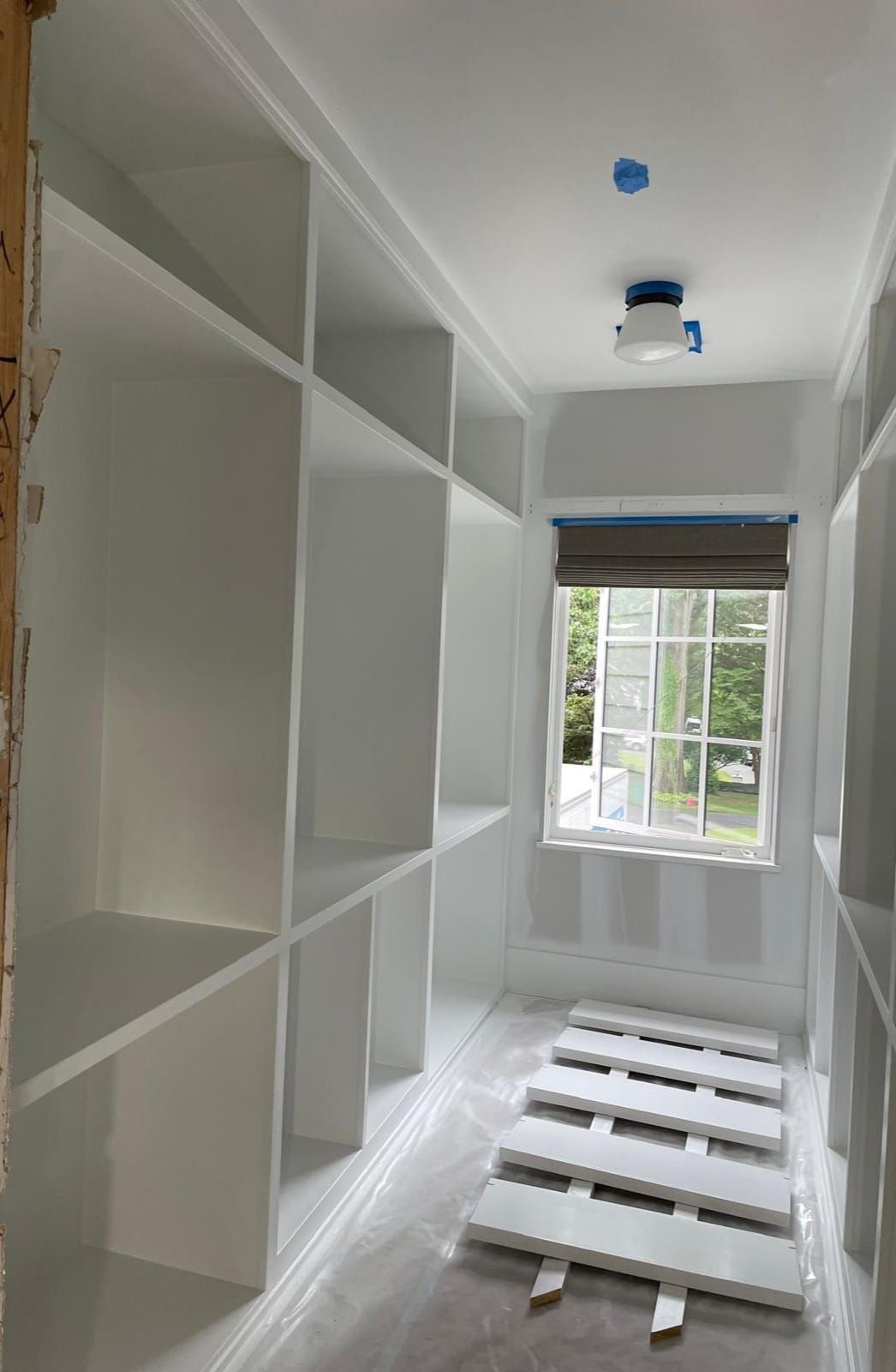 A walk in closet with lots of shelves and a window.