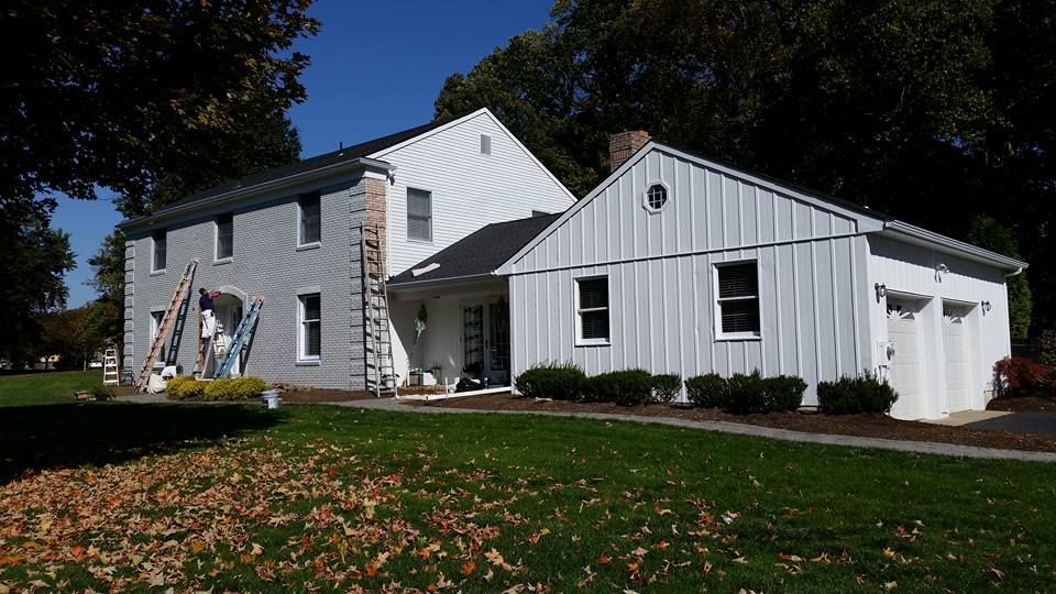 A large white house with a garage is being painted.