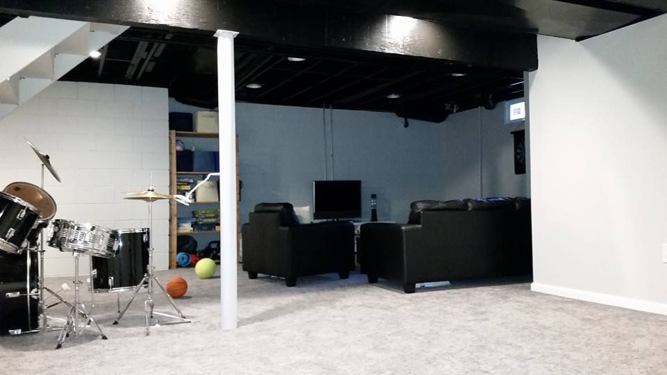 A basement with a drum set and a television