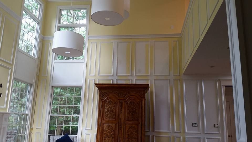 A living room with yellow walls and white trim and a wooden cabinet.