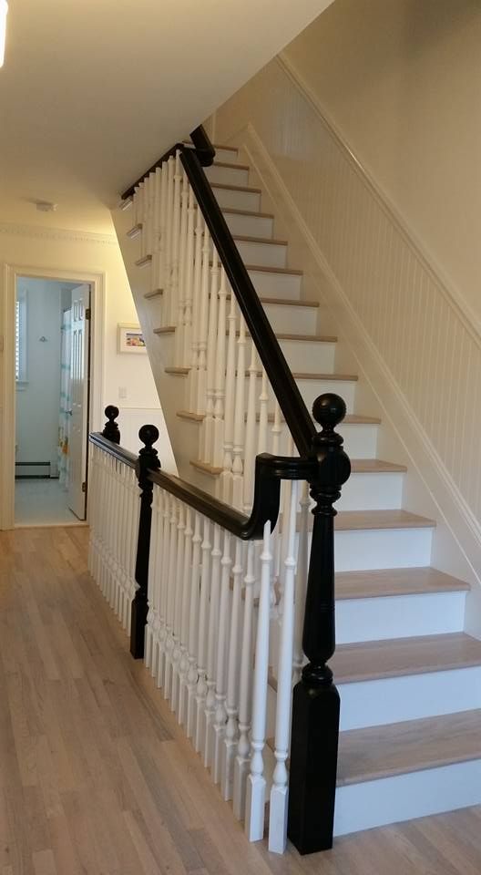 A staircase with a black railing and white steps in a hallway.