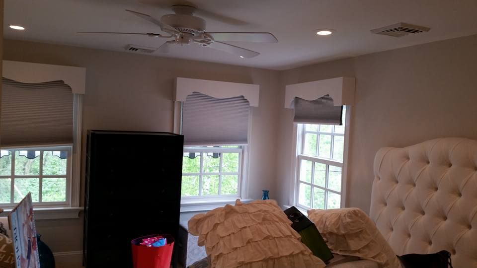 A bedroom with a bed , ceiling fan , and two windows.