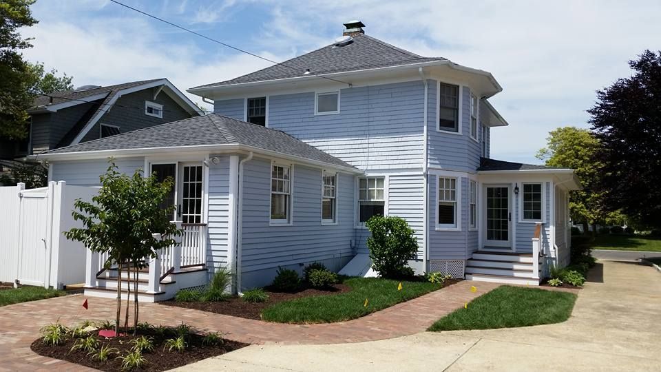 A blue house with a gray roof and a white fence