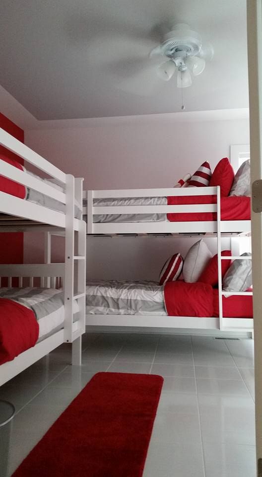 A room with three bunk beds and a red rug.