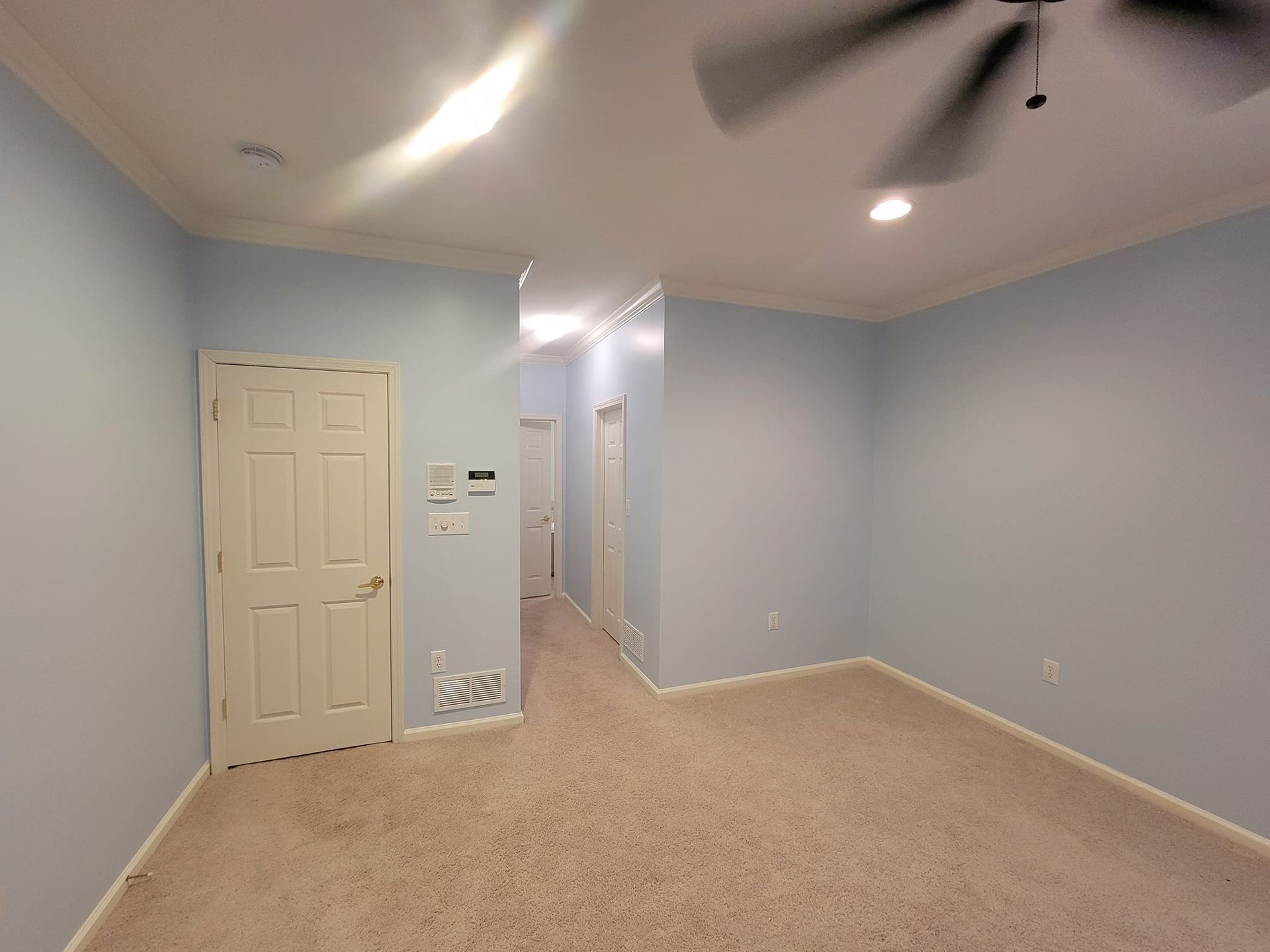 An empty room with blue walls and a ceiling fan