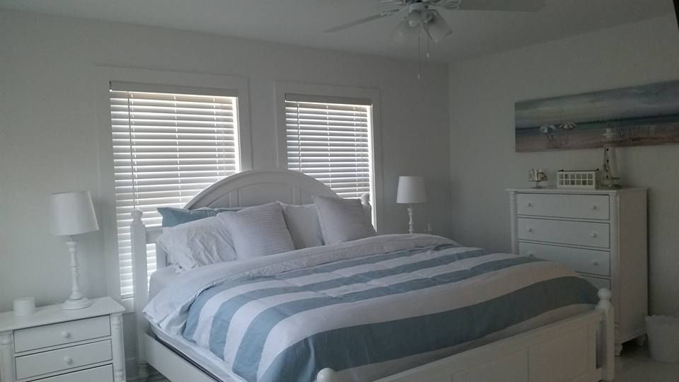 A bedroom with a bed , dresser , nightstand and a ceiling fan.