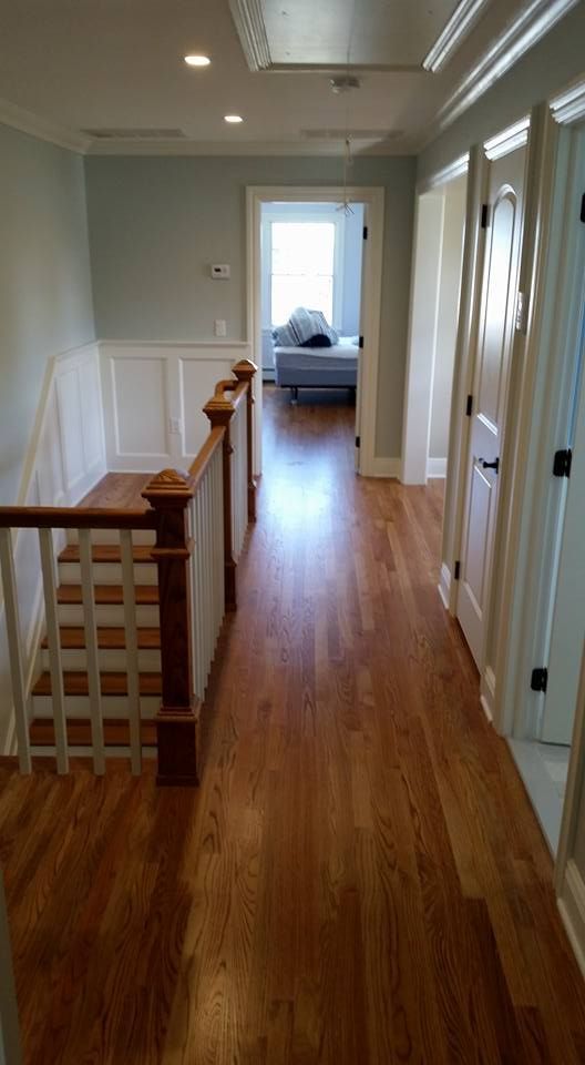 A hallway with hardwood floors and stairs leading to a bedroom.