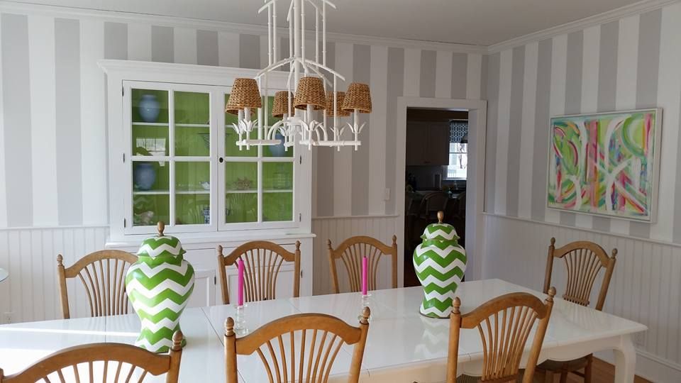 A dining room with a table and chairs and striped wallpaper