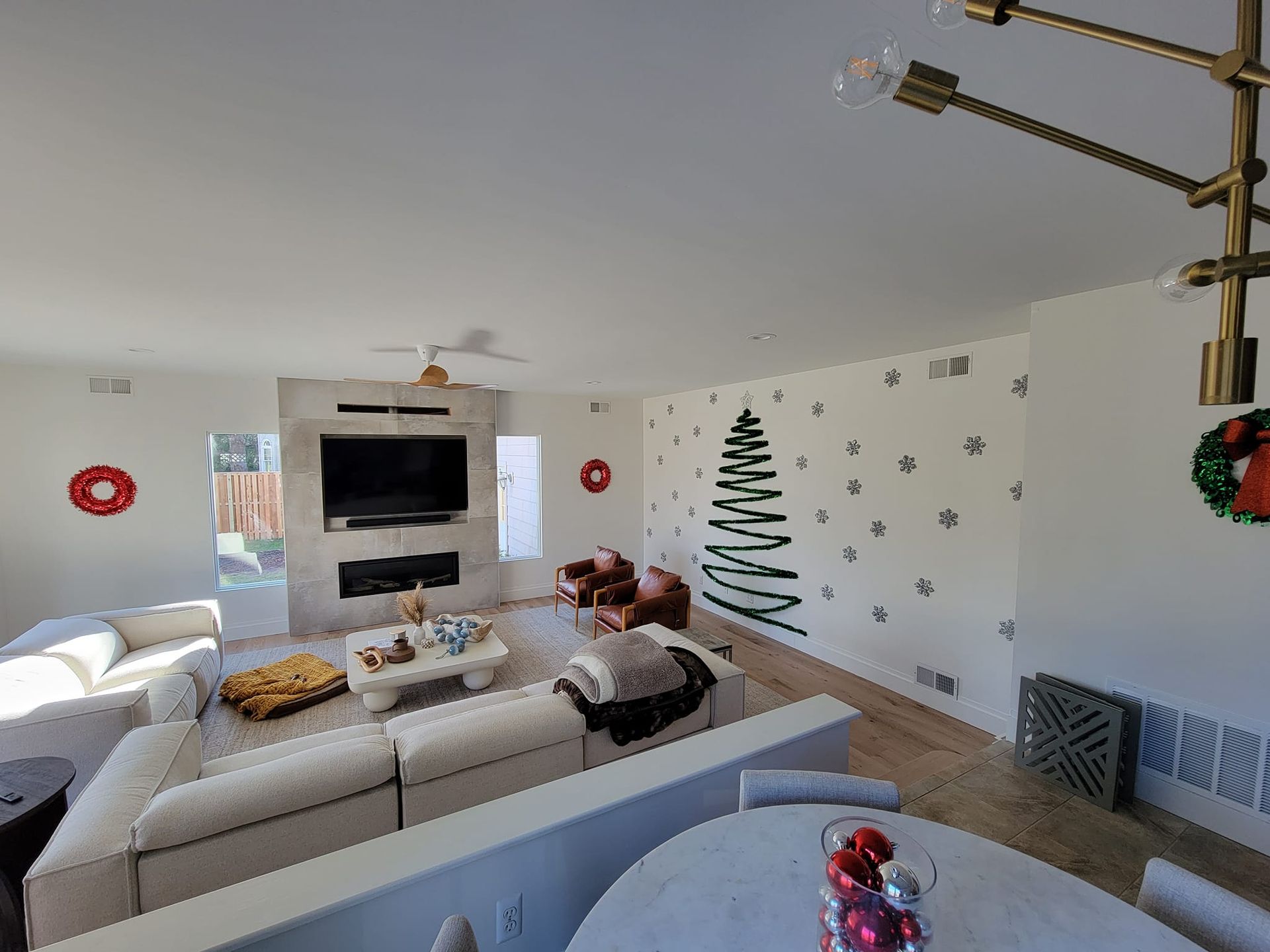 A living room decorated for christmas with a christmas tree on the wall.