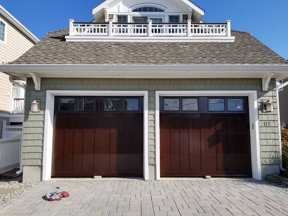 A house with two garage doors and a balcony on top